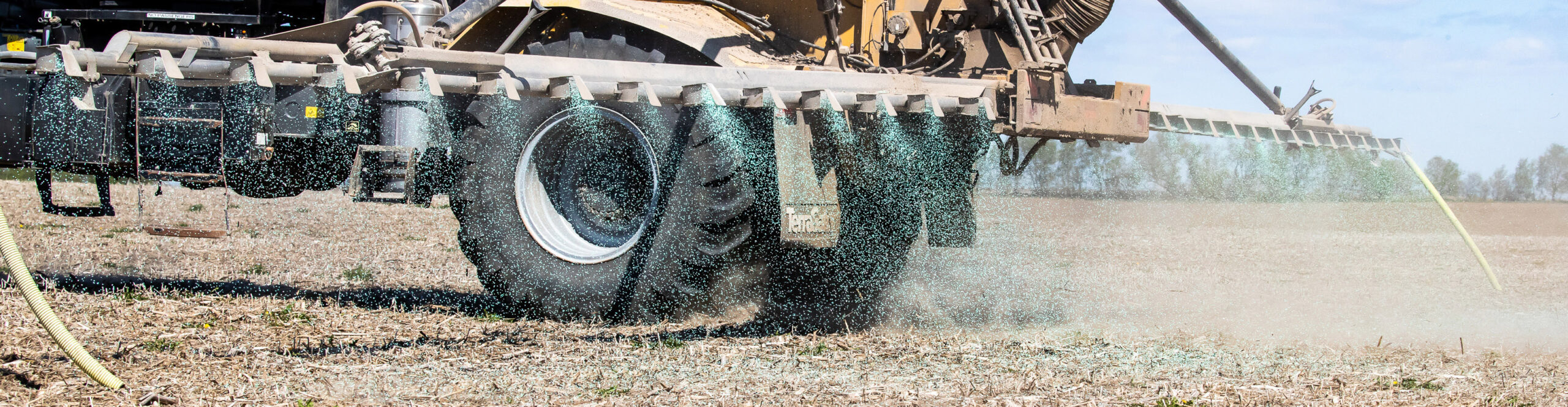 Sprayer attachment on back of tractor spraying a field with crop nutrients
