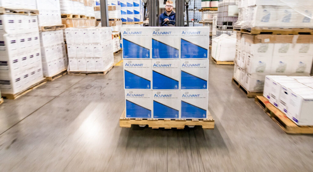 Acuvant product boxes on a wooden pallet being moved by a man on a forklift