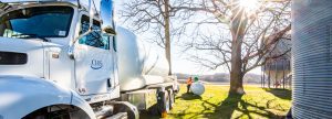 Man refueling a propane tank with hose from propane truck