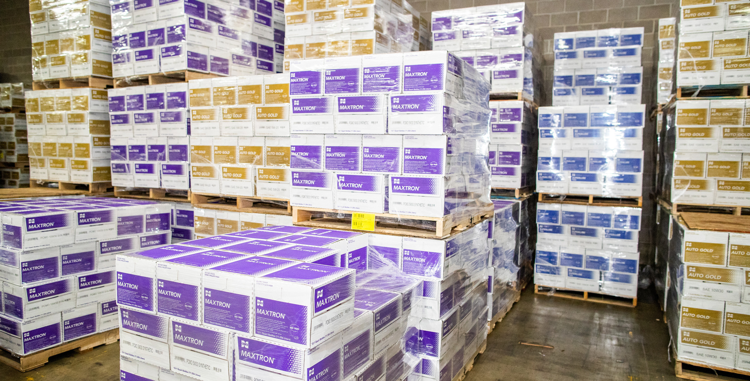 Maxtron and Auto Gold product boxes sitting on pallets in a warehouse