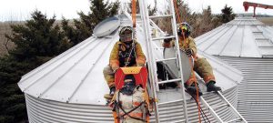 Two firefighters sitting on top of a grain bin performing a grain bin safety exercise