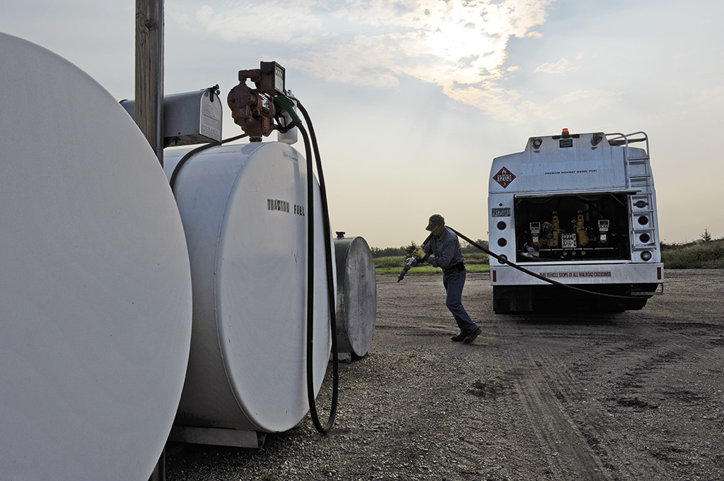 Man walking hose from propane truck to refill propane tank