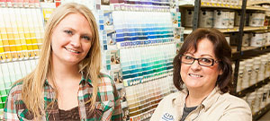 Two women standing beside a paint sample wall in a hardware store